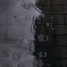 the umbrella is reflecting in the water on the sidewalk and it's reflection looks like raindrops