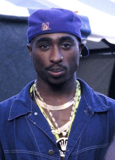 a young man wearing a blue hat and necklace