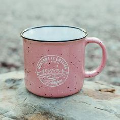 a pink coffee mug sitting on top of a rock