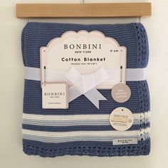 a blue and white striped blanket hanging on a wooden hanger with tags attached to it