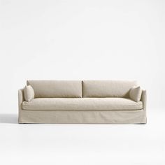 a white couch sitting on top of a white floor next to a wall with a light colored background