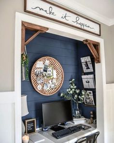 a desk with a computer on top of it in front of a wooden sign that says smile at happen