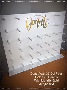 a white acrylic sign with gold lettering on it that says donut wall 360 doi pegs holds 72 donuts with metallic gold acrylic text