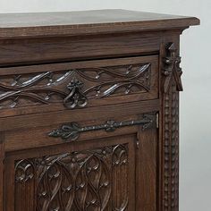 an ornate wooden cabinet with carvings on the front and side panels, in dark wood