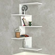 three white shelves on the wall with books and vases in them, one is empty