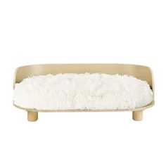 a dog bed with white fur and wooden legs