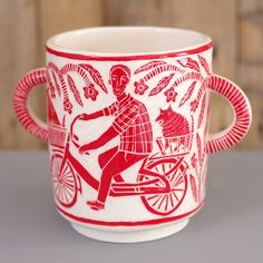 a red and white cup with an image of a man riding a bike on it