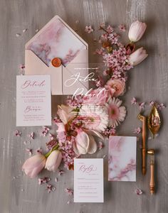 the wedding stationery is laid out with pink flowers