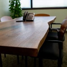 a conference table with chairs and a cell phone on it in an office setting by a window