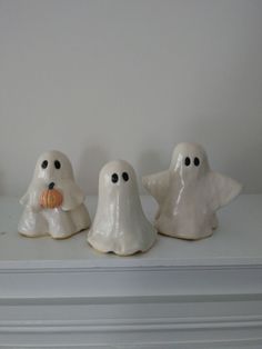 three white ghost figurines sitting on top of a shelf