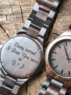 two wooden watches sitting on top of a tree stump with the words, every second i love you more