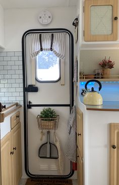 the inside of a camper with an open door and small potted plant on the window sill