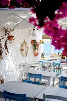 an outdoor dining area with tables, chairs and flowers on the wall behind them in front of a window