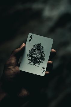 a person holding up a playing card in their hand