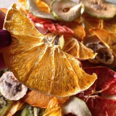 someone holding an orange slice over a pile of dried fruit