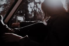 a woman sitting in the passenger seat of a car looking at her cell phone