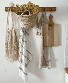 a wall mounted shelf with towels and bags hanging from it's hooks on the wall