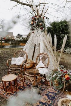 an outdoor area with wicker chairs, rugs and a teepee tent in the background