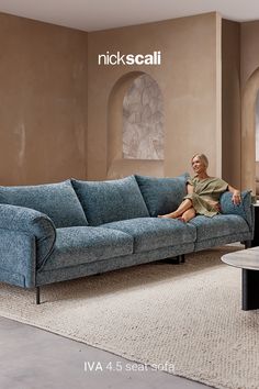 a woman sitting on top of a blue couch in a living room next to a coffee table