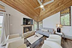 a living room filled with furniture and a flat screen tv on top of a wooden ceiling