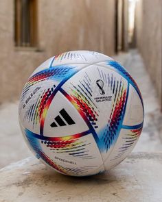 a white soccer ball sitting on top of a stone floor next to an alley way