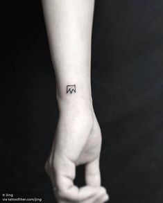 a woman's hand with a small black and white tattoo on her left wrist