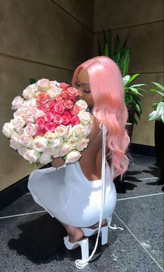 a woman with pink hair holding a large bouquet of white and red roses in her hands