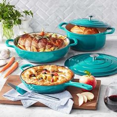 three blue casserole dishes on a marble countertop with fresh fruit and vegetables