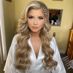 a woman with long blonde hair wearing a white shirt and flower headband, standing in front of a mirror