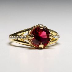 Gorgeous gold plated Garnet Crystal Ring-  gemstone- with dazzling crystals. size 7 1/4. It shines like real gold. GREAT Gift! No Tarnish It will come in a gift bag Gold Ruby Ring With Center Stone As Gift, Gold Ruby Ring With Center Stone For Gift, Gold Crystal Ring With Round Cut And Accent Stones, Gift Gold Ruby Ring With Center Stone, Gold Ruby Ring With Accent Stones For Anniversary, Anniversary Ruby Ring With Gold Accent Stones, Gold Birthstone Ring With Cubic Zirconia, Anniversary Gold Ruby Ring With Accent Stones, Gold Jeweled Crystal Ring Gift