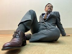 a man in a suit and tie is sitting on the floor with his feet up