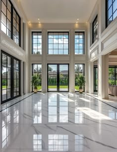 an empty room with large windows and white marble flooring in front of the doors