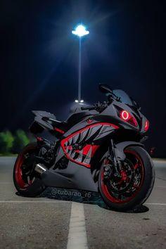 a red and black motorcycle parked in a parking lot next to a street light at night