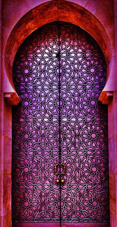 an ornate door is shown in front of a pink wall