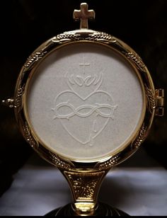 a close up of a gold colored clock on a black surface with an ornate frame around it