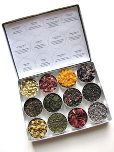 a box filled with lots of different types of teas and flowers on top of a white table