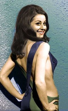 a woman standing in front of a wall with her back to the camera, wearing a bathing suit