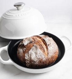 a loaf of bread sitting in a pan on top of a counter next to a white pot