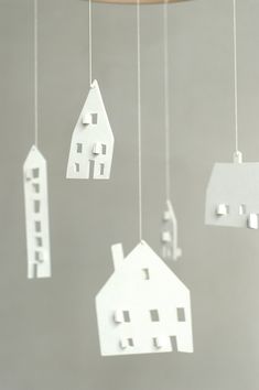 some paper houses hanging from strings in front of a gray wall