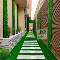 an outdoor walkway with artificial grass between two buildings