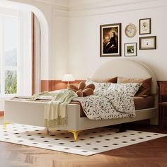 a bed with pillows and blankets on top of it in a room next to a window