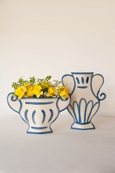 two blue and white vases with yellow flowers in them