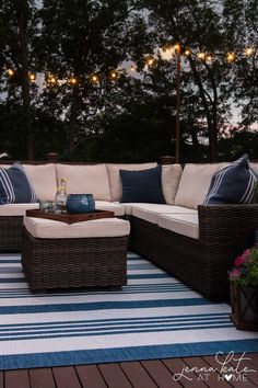 an outdoor living area with wicker furniture and lights strung above the patio decking