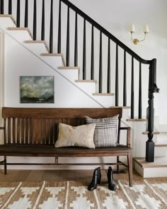 a wooden bench sitting under a staircase next to a set of banisters with pillows on it