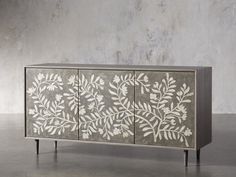 an artisticly designed sideboard with leaves painted on the front and sides, against a grey background