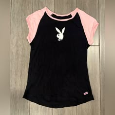 This Black Vintage Tee Features A Playboy Logo On The Front, A Round Neckline With Pink Trim, And Pink Cap Sleeves. The T-Shirt Is Made Of 100% Combed Cotton Material. The Playboy Bunny Logo Is Prominently Displayed On The Front Of The Black Shirt With Pink Accents. This Item Is Perfect For Casual Occasions And Is Available In Size Medium. The Shirt Has A Regular Fit And Is Very Stretchy. It Is A Great Addition To Any Wardrobe And Is Sure To Turn Heads. It’s Brand New, Never Wort, But I Marked I Bunny Clothes, Bunny T Shirt, Bunny Logo, Pink Cap, Bunny Outfit, Aesthetic Fits, Pink Trim, Kawaii Stuff, Capped Sleeves