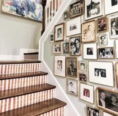 a staircase with many framed photos on the wall and wooden handrails above it