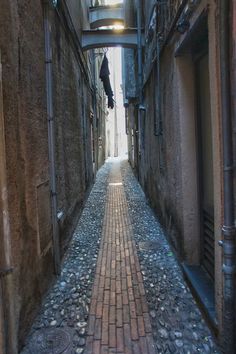 an alley way with cobblestones and lamps on either side, between two buildings