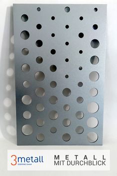 the metal sheet has holes in it and is attached to a wall with dots on it