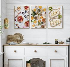 three paintings hanging on the wall above a white cabinet in a kitchen with an oven